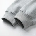 Close-up detail of grey hoodie sleeve showing high-quality elastic ribbed cuffs and premium cotton fleece fabric texture.