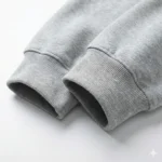 Close-up detail of grey hoodie sleeve showing high-quality elastic ribbed cuffs and premium cotton fleece fabric texture.